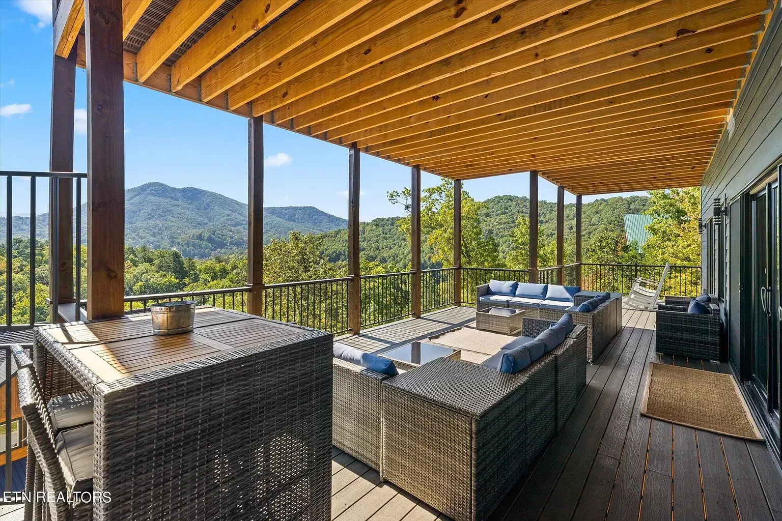 A large deck with a table and chairs and a view of the mountains.