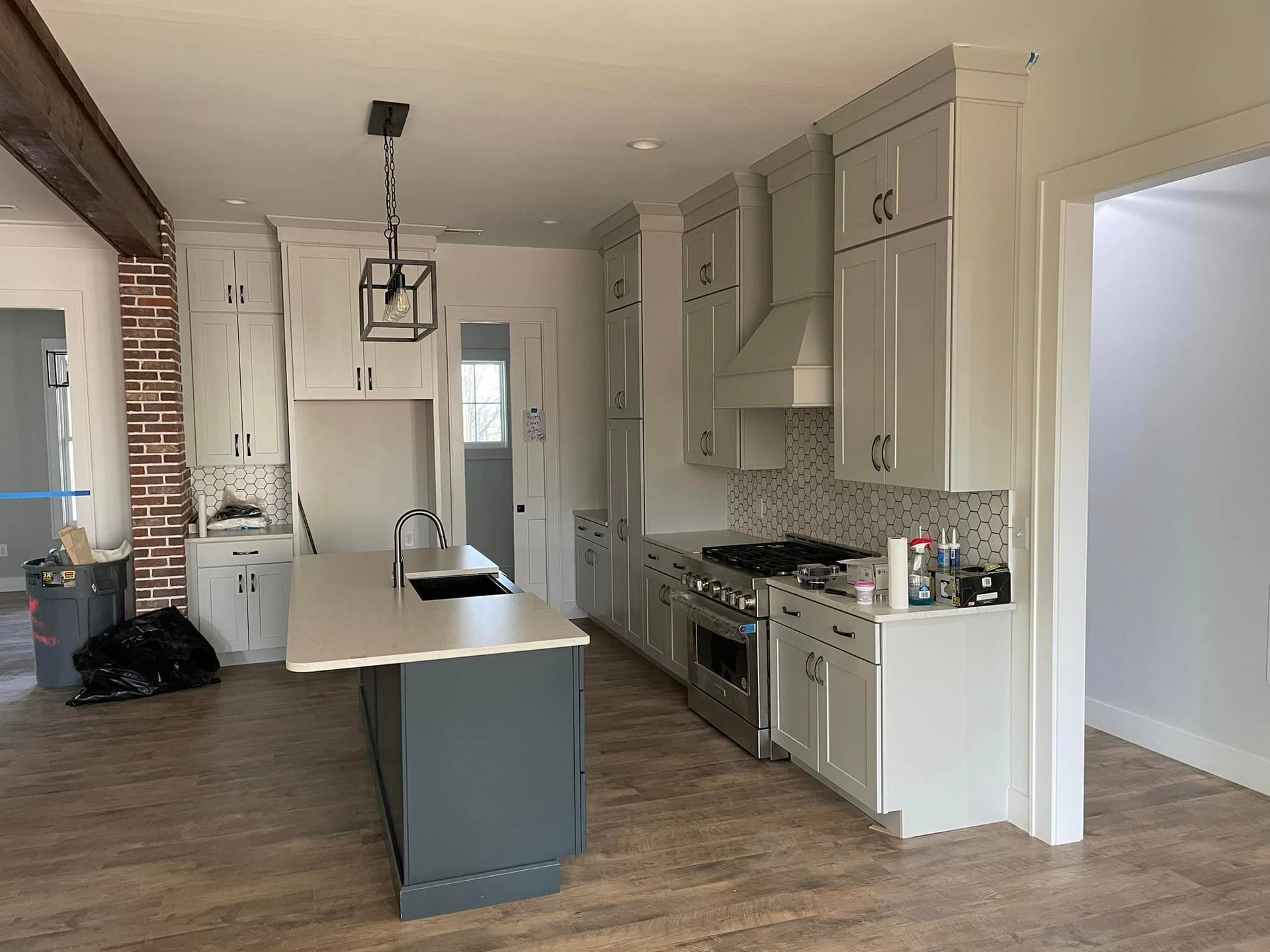 A kitchen with white cabinets , stainless steel appliances , and a large island.