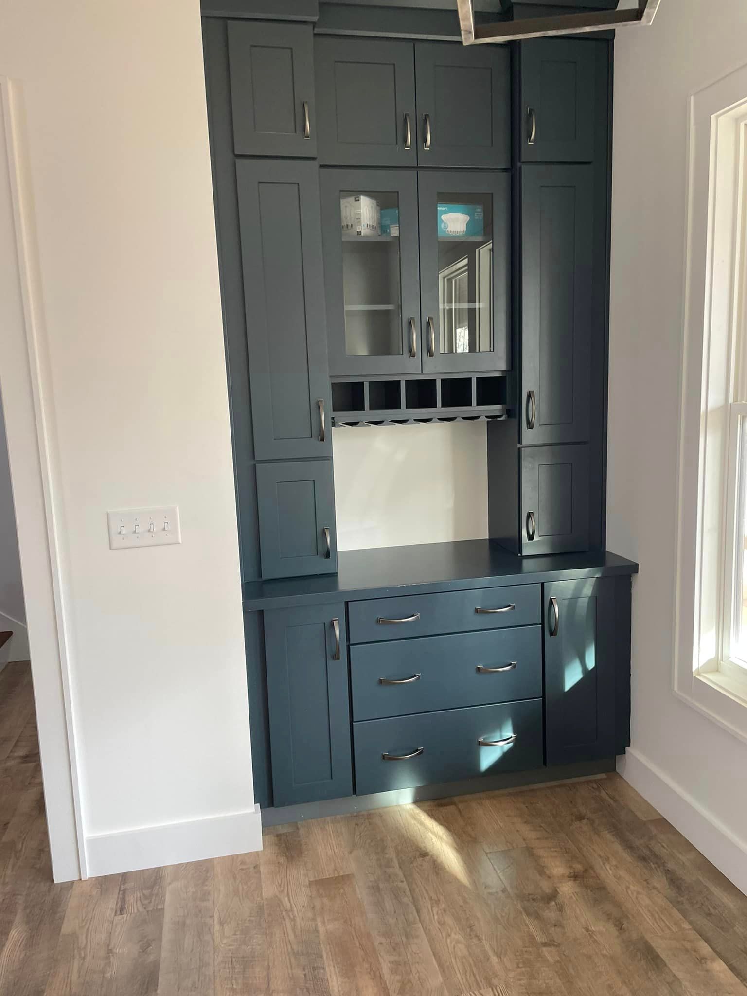 A kitchen with a lot of cabinets and drawers and a window.