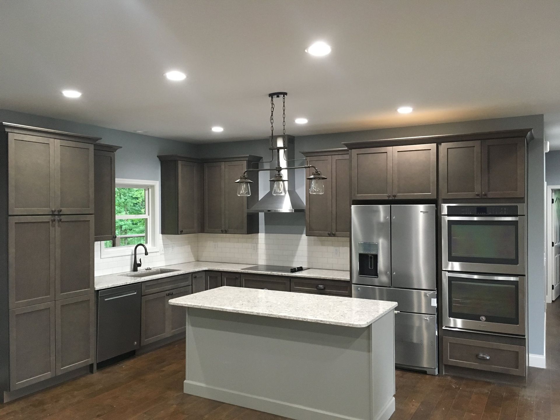 A kitchen with stainless steel appliances and gray cabinets.