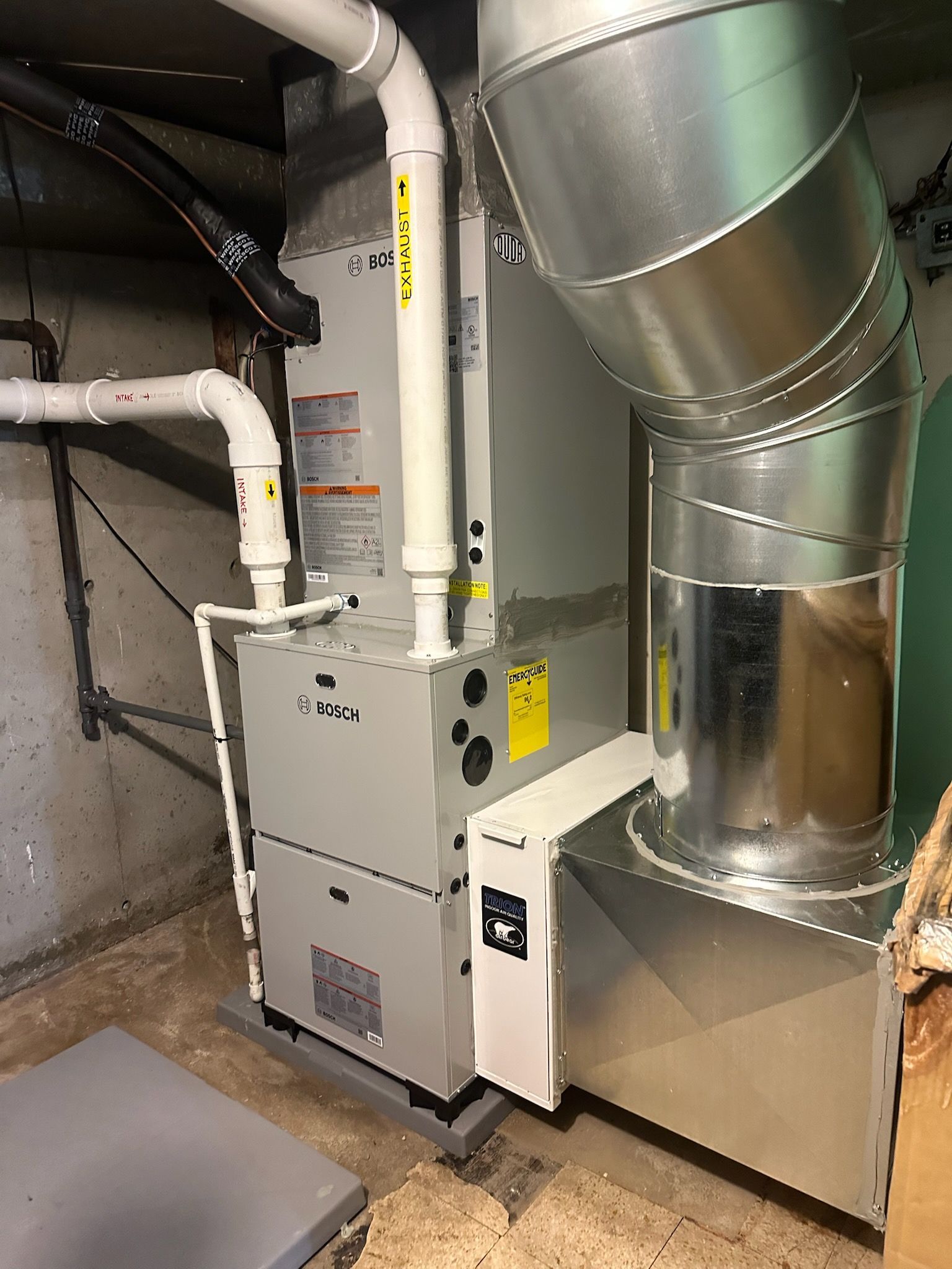 HVAC furnace and ductwork in a utility room with white pipes and metal vents