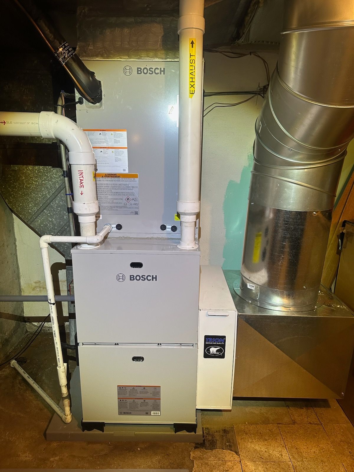 Bosch HVAC furnace in a utility room with white vent pipes and ductwork