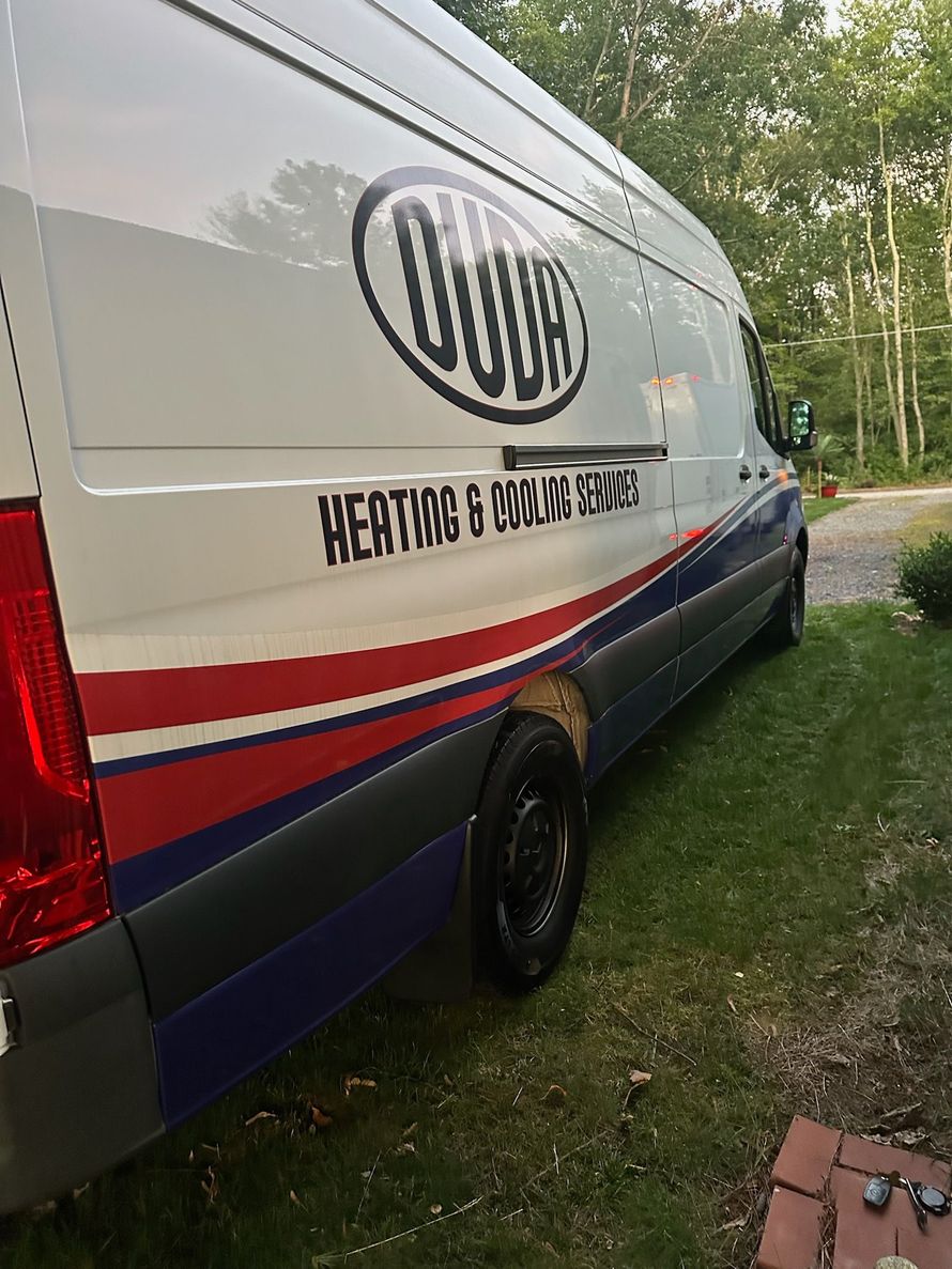 White and navy service van with red stripe parked on grass by a driveway