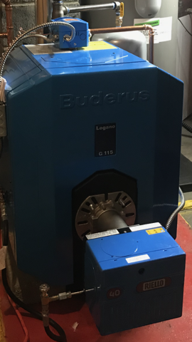 Blue industrial boiler unit with front access panel and open burner compartment in a utility room