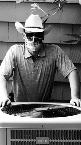 Person in a cowboy hat and skull face covering standing behind an outdoor grill.
