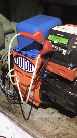 Orange and blue generator with red handles on a concrete floor, black power unit attached