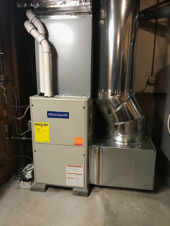 Technician wearing protective gloves services the interior of a residential heating boiler.