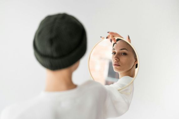 Person adjusting a round mirror while looking at their reflection in a bright room