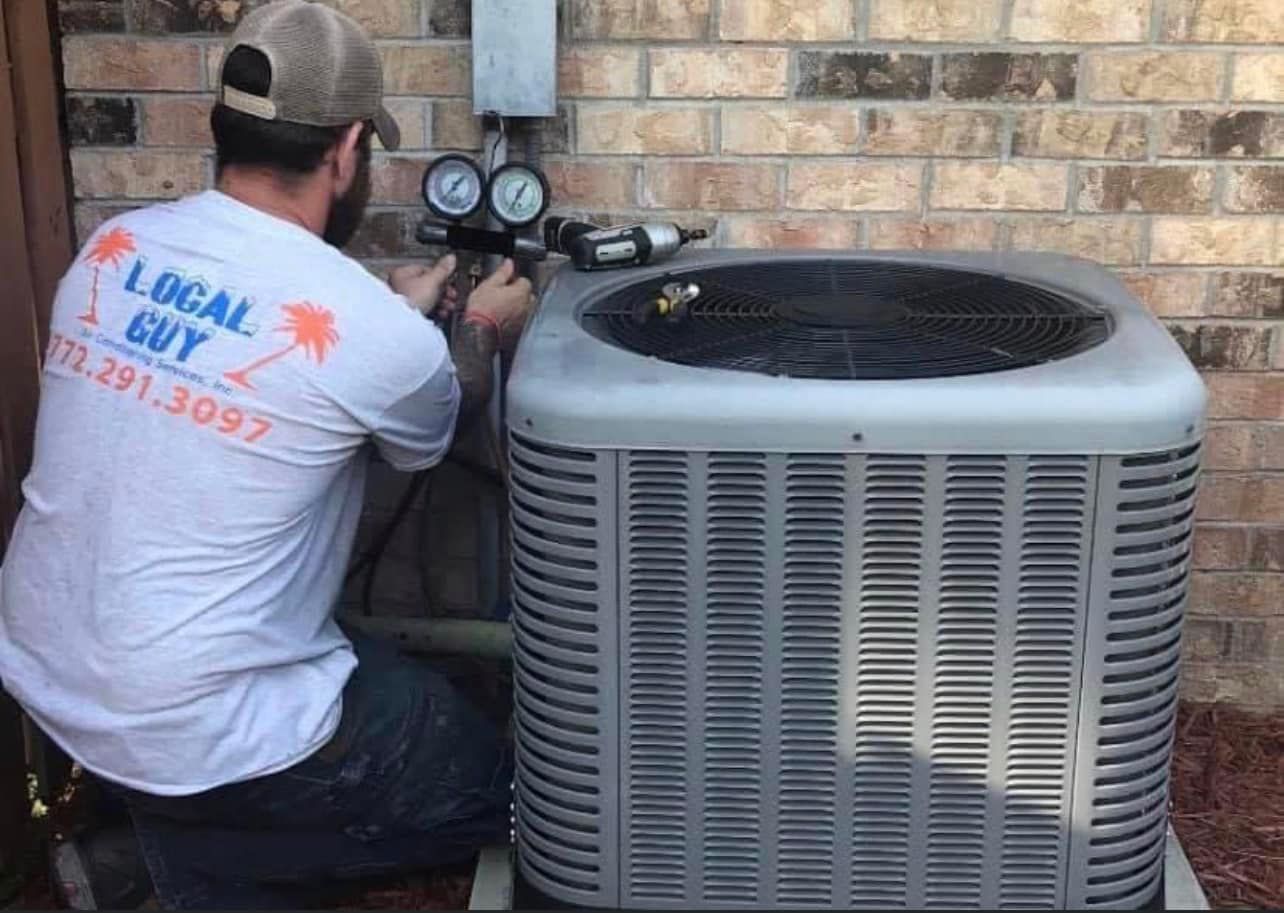 Local Guy technician is working on an air conditioner outside of a brick building.