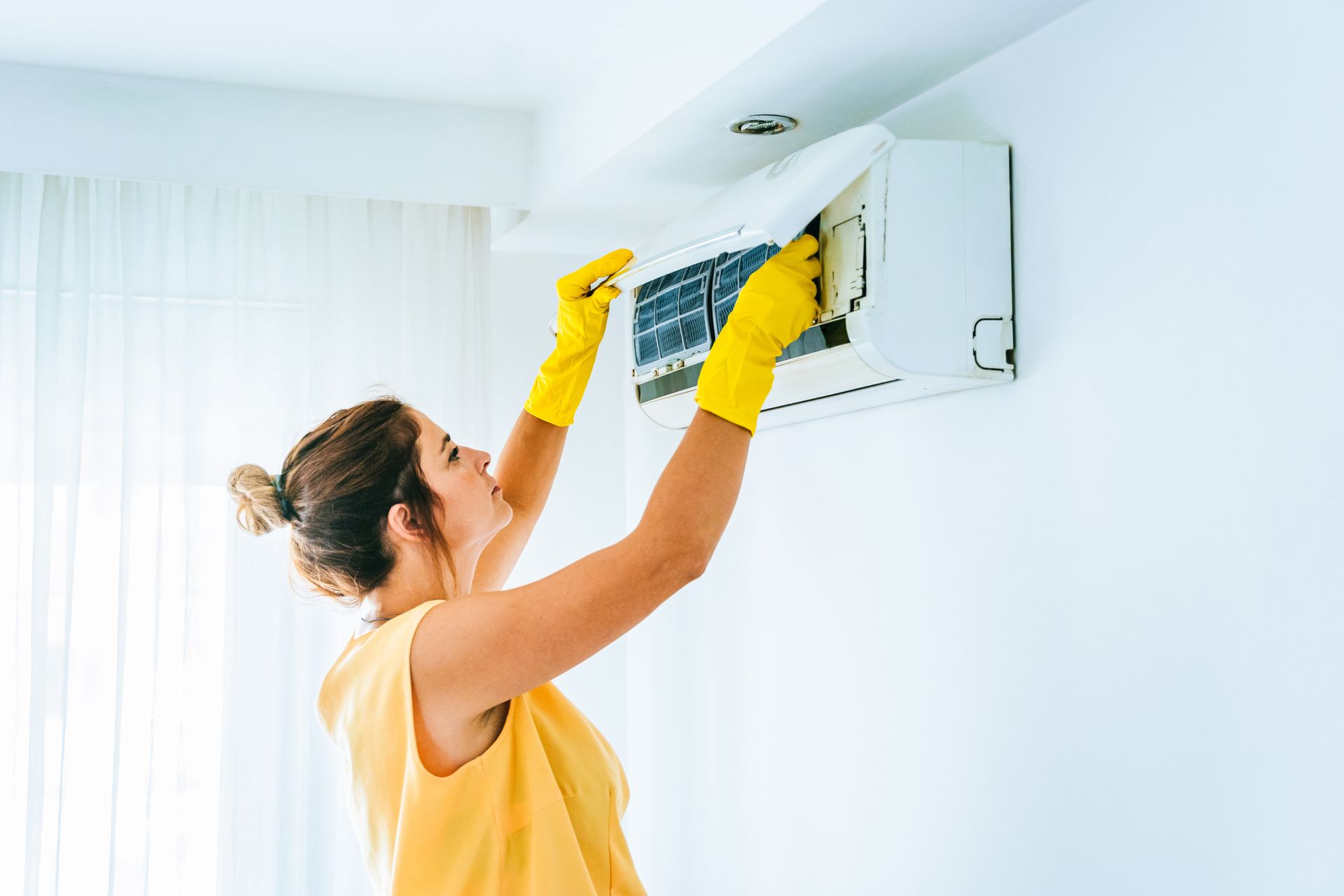 Palm City homeowner preparing for holiday guests while adjusting AC filter in living room.