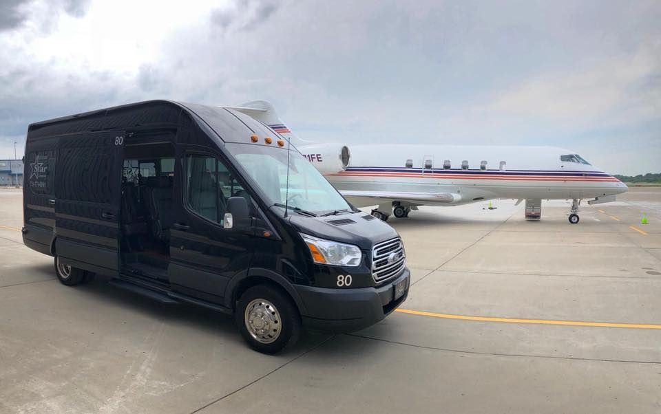 A black van is parked next to a private jet on a runway.