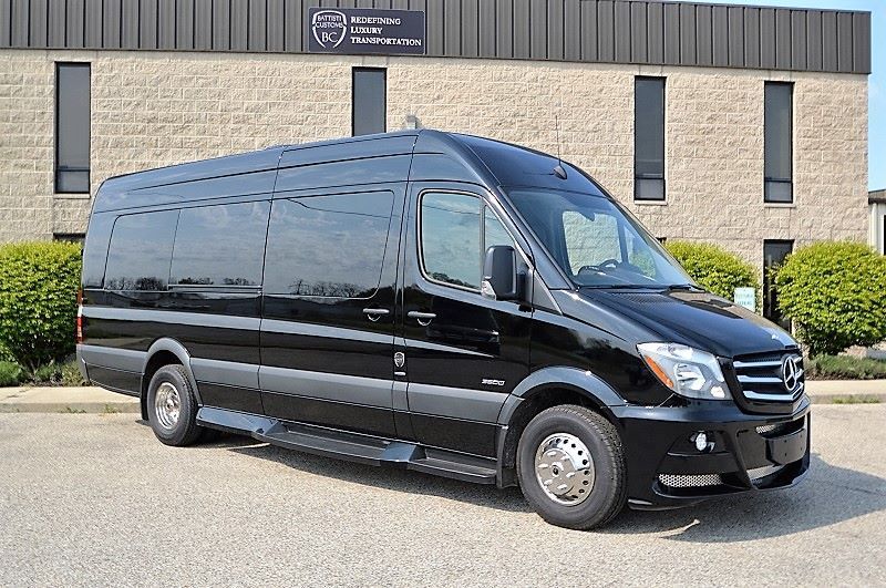 A black van is parked in front of a brick building.
