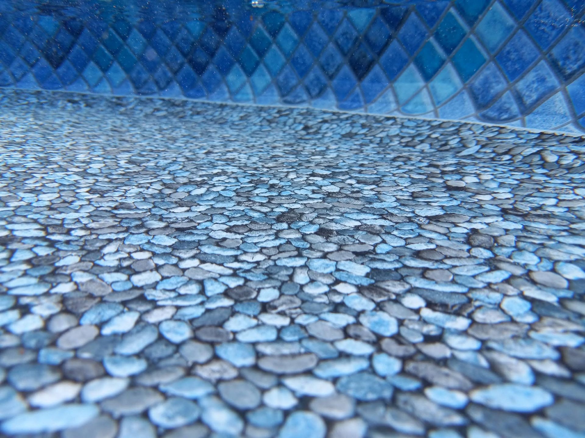 Blue pebble mosaic floor and wall with diamond pattern in an empty room