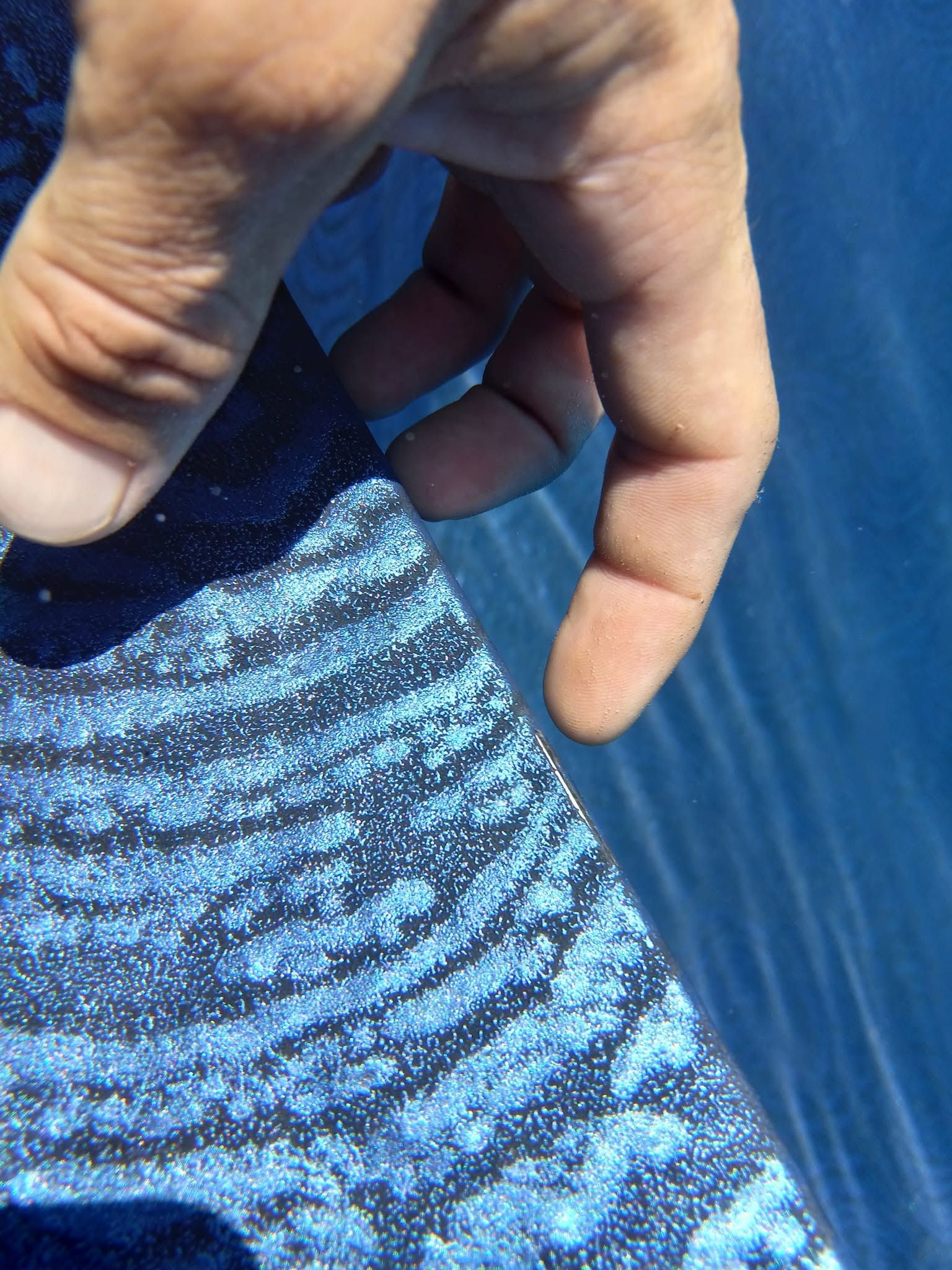 Hand holding a blue patterned fabric against a blue background