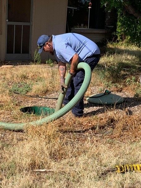 Septic tank truck with hose connected to residential septic tank. Septic tank truck with hose connected to residential septic tank.