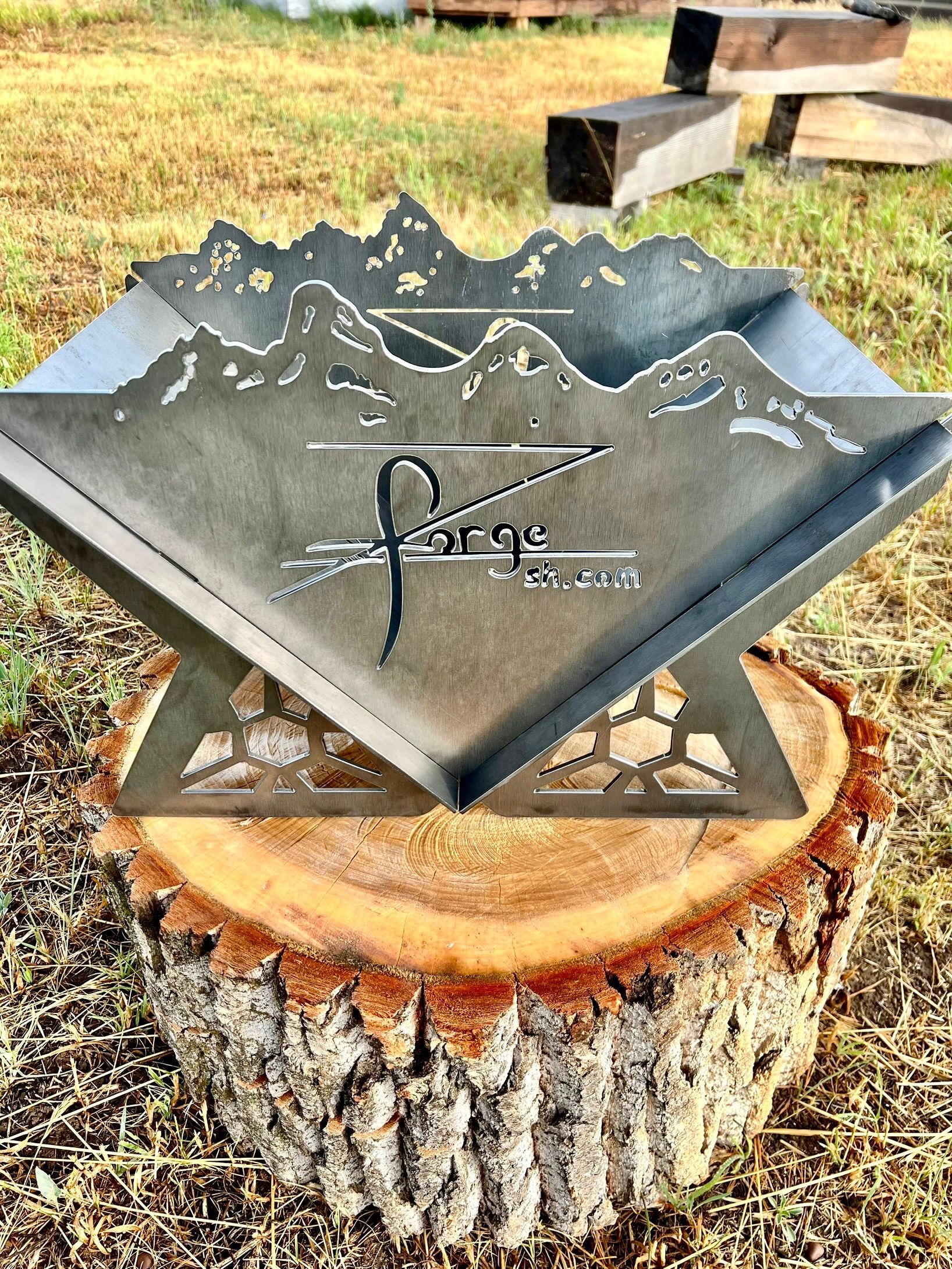 A metal fire pit is sitting on top of a tree stump.