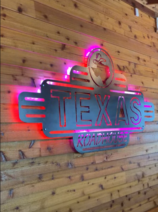 A sign on a wooden wall that says texas roadhouse
