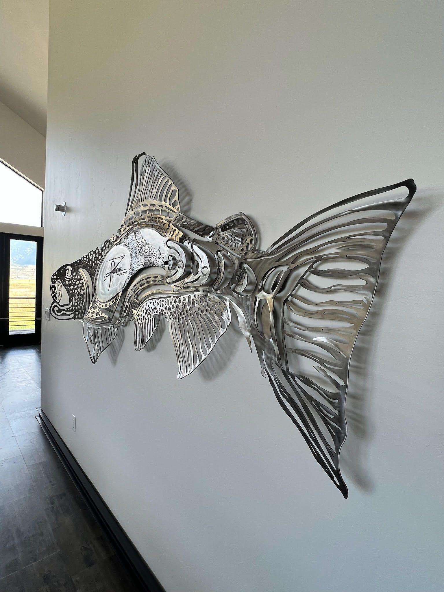 A sculpture of a fish is hanging on a wall in a hallway.