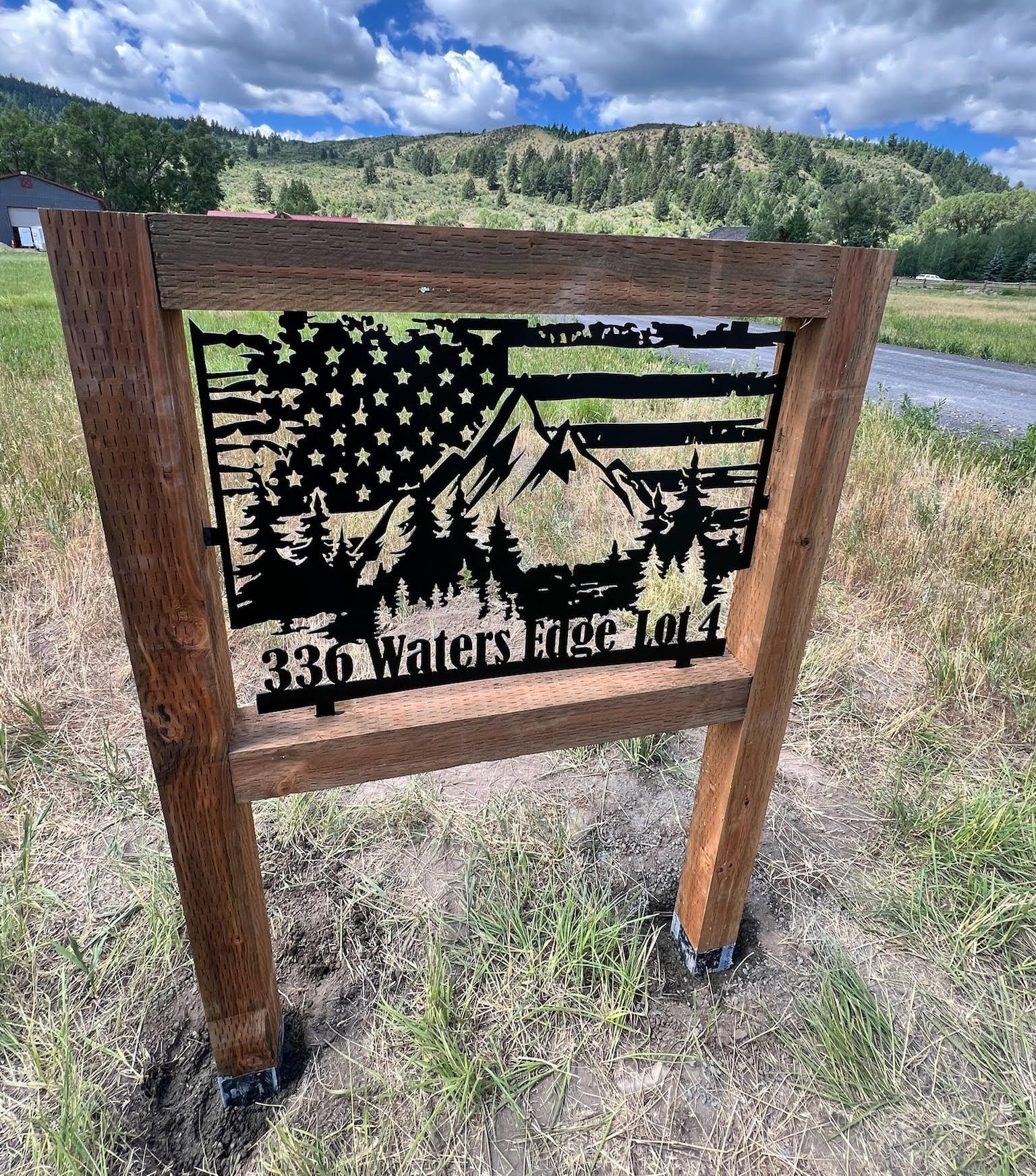 A wooden sign with an american flag and mountains on it.