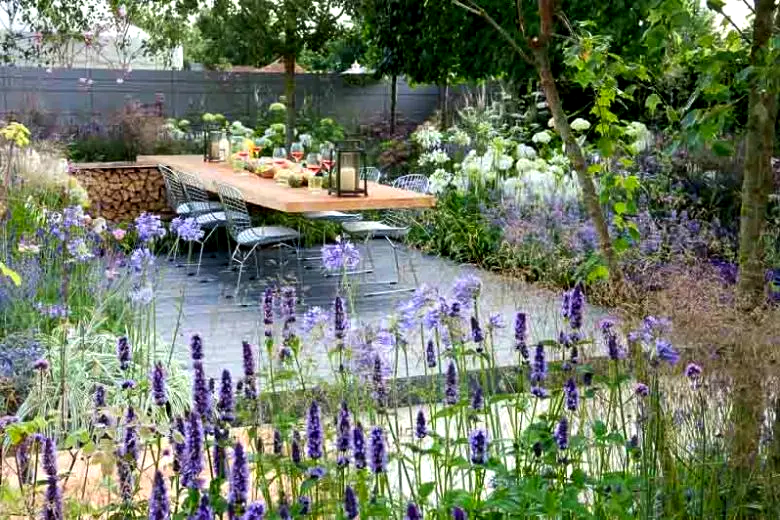 Terras met vaste planten, siergrassen en een rustige zitplek.