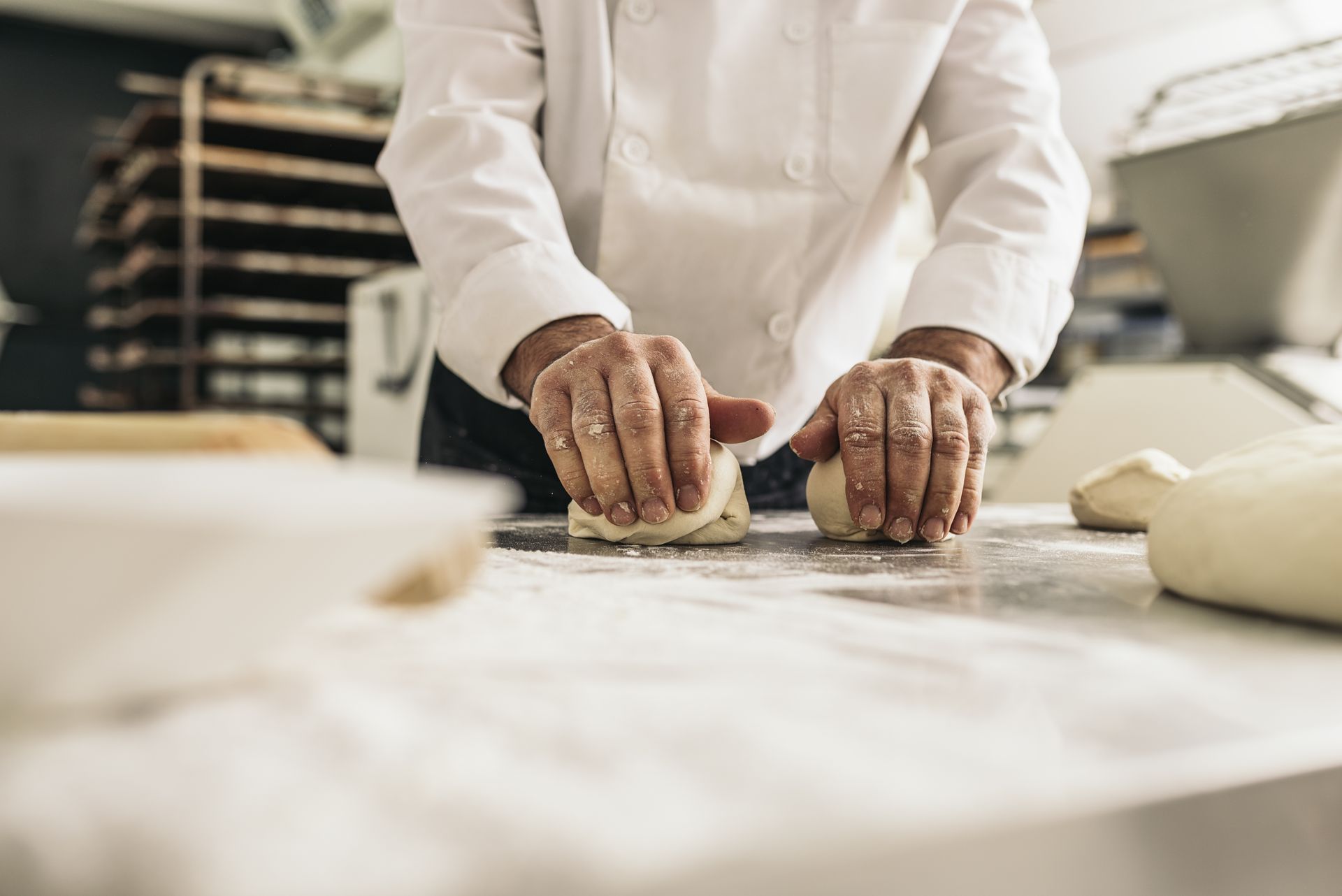 A baker is kneading dough on a table in a bakery.