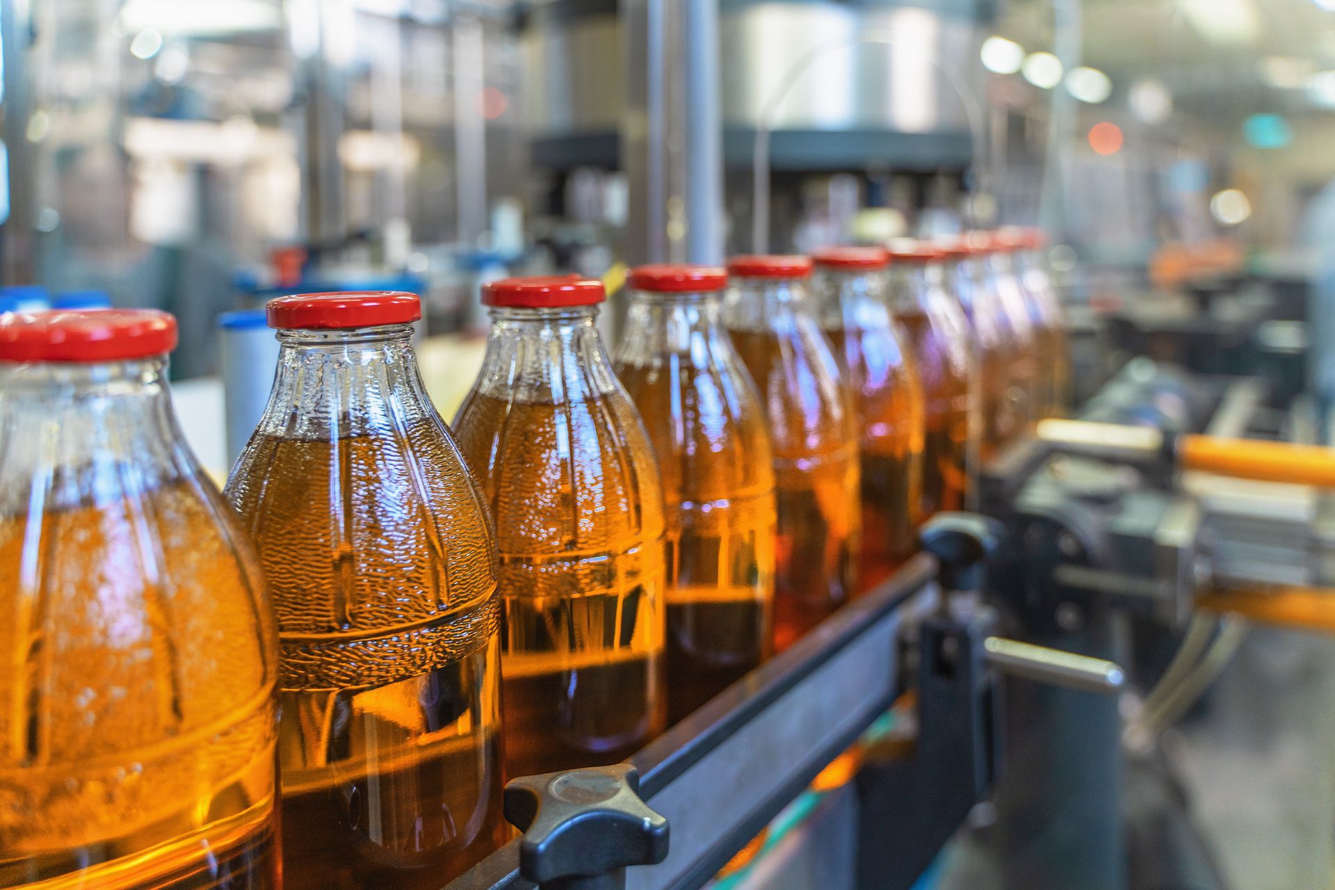 A conveyor belt filled with bottles of soda in a factory.