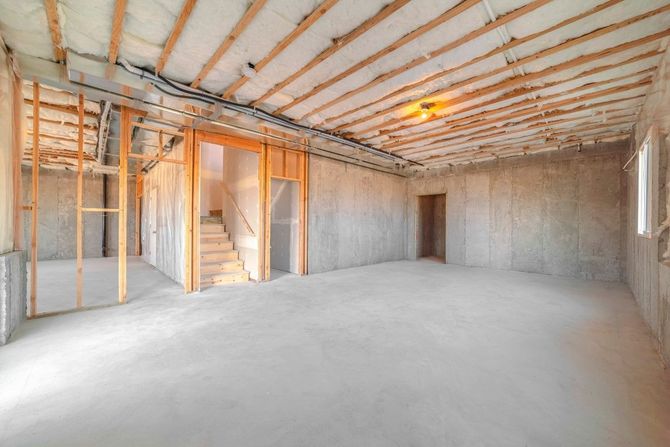 Partially finished room with exposed framing, insulation, and concrete floor