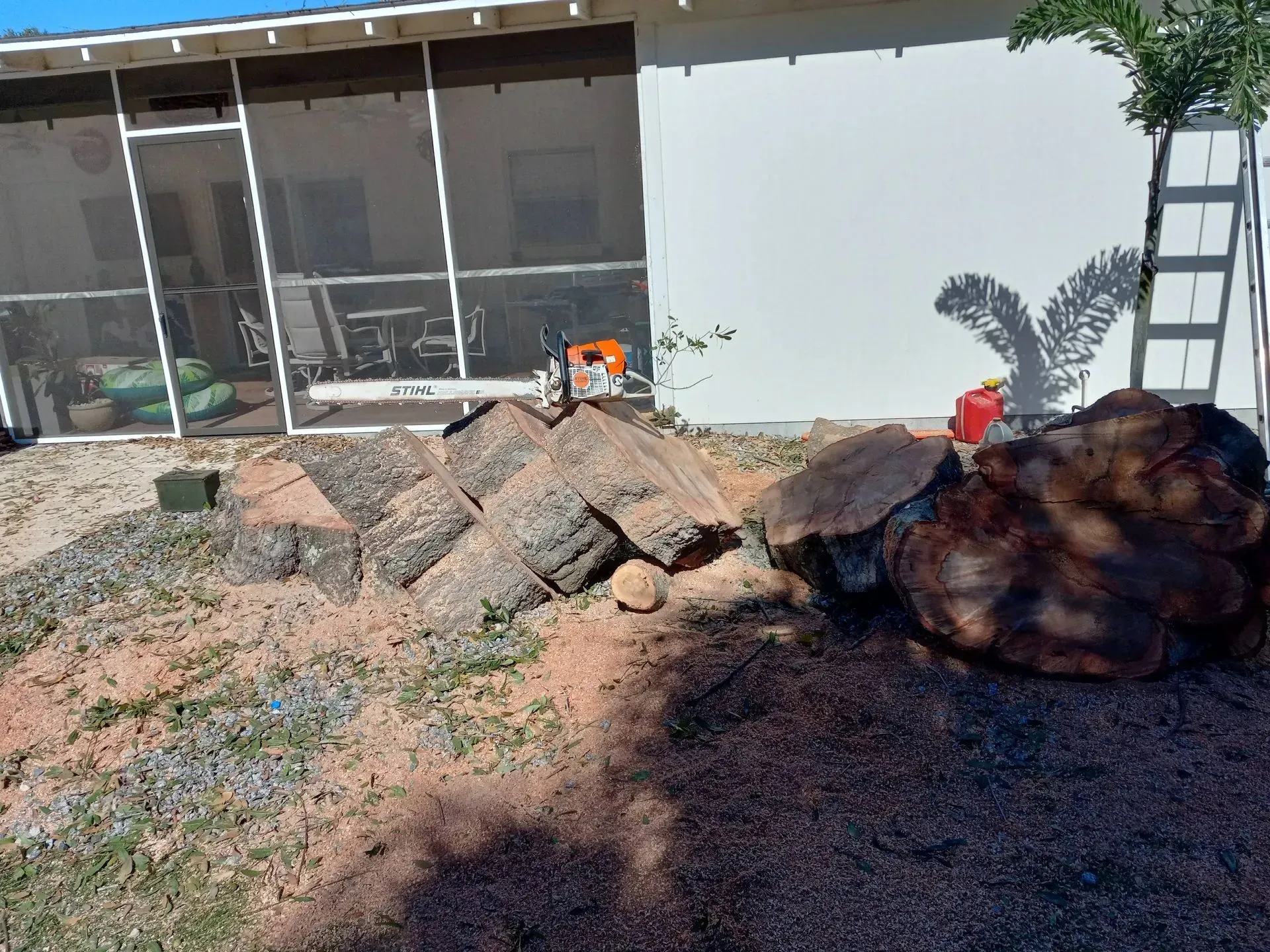 Rock garden with large boulders and gravel beside a house in bright sunlight