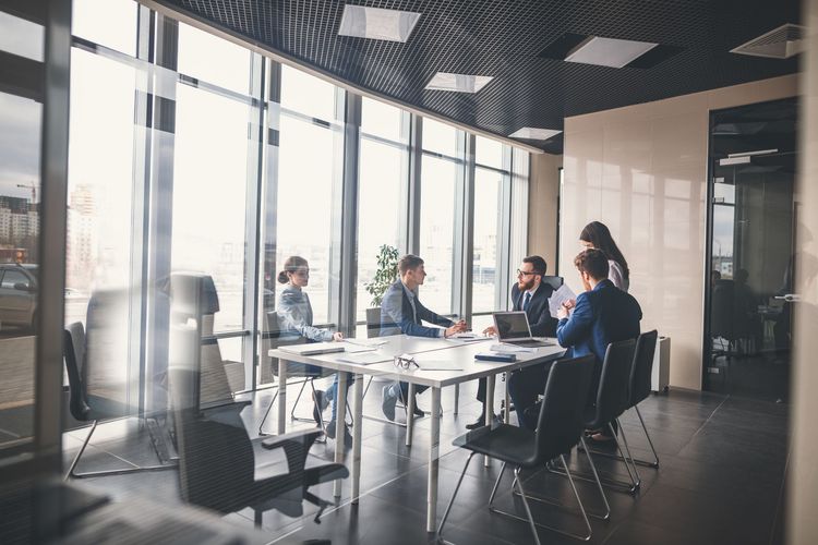Business meeting around a glass conference table in a bright modern office