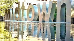 A large metal sculpture of the word downtown is reflected in a pool of water.