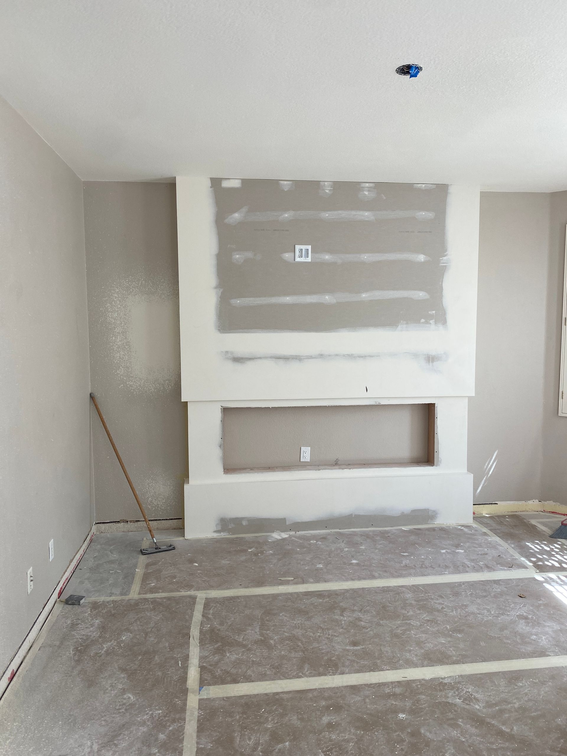 Partially finished room with drywall, taped seams, and a recessed wall opening