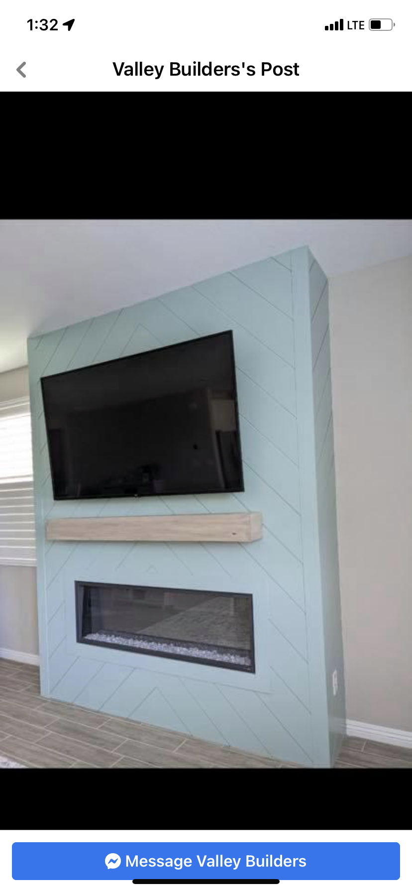 Modern living room wall with mounted flat-screen TV above a glass-front fireplace insert