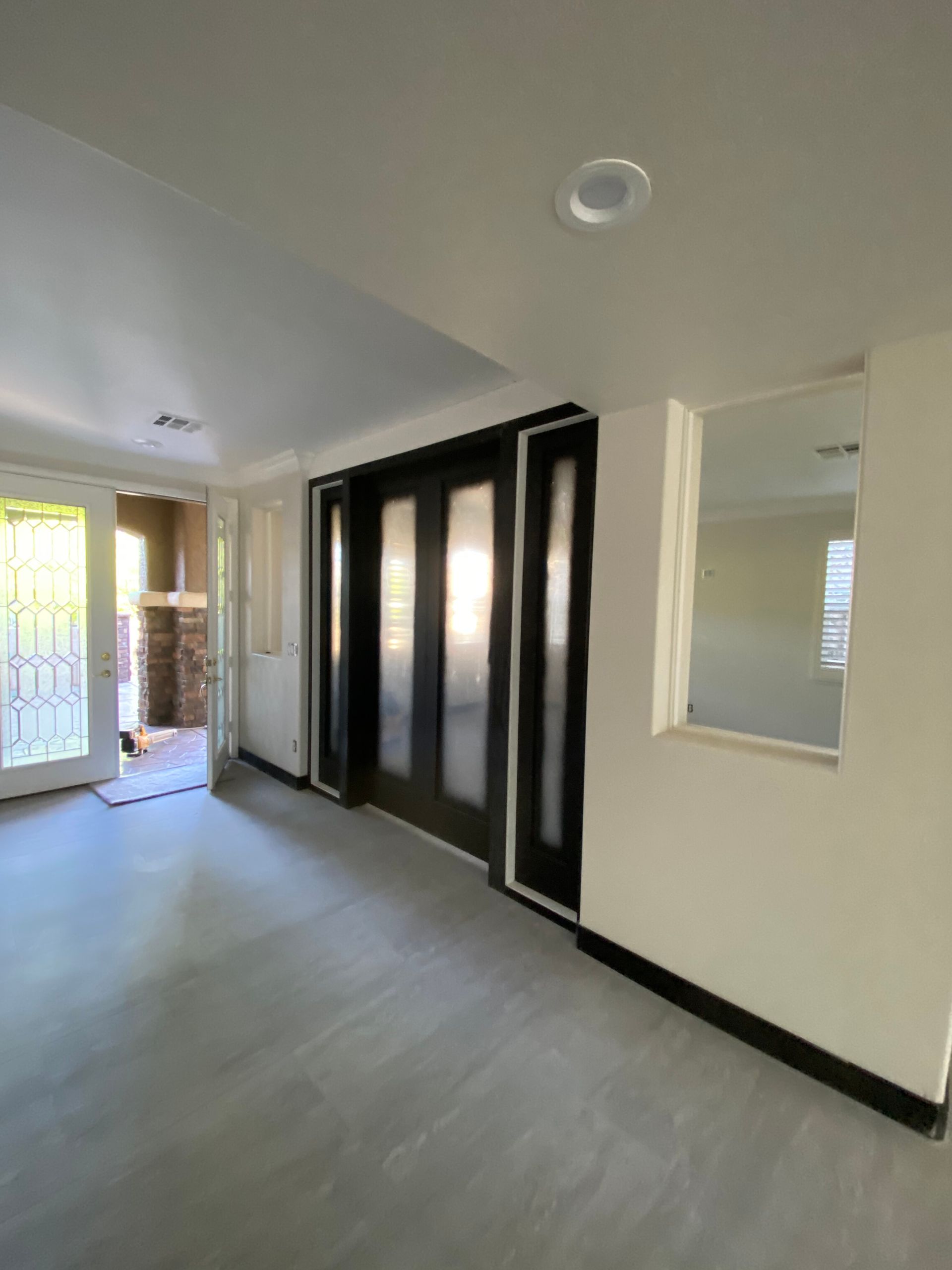 Empty hallway with light gray walls, black trim, and a large black-framed window