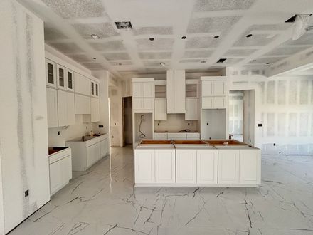 Bright white modern kitchen with island, built-in cabinets, and marble-look floors.