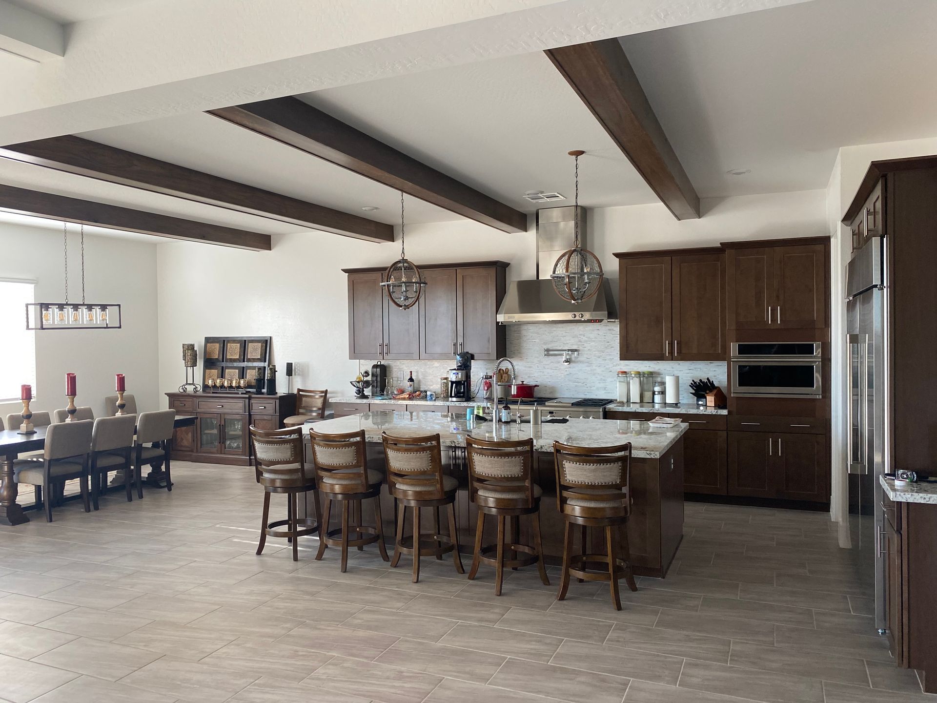 Spacious modern kitchen with island, wood beams, pendant lights, and dining table set for a meal