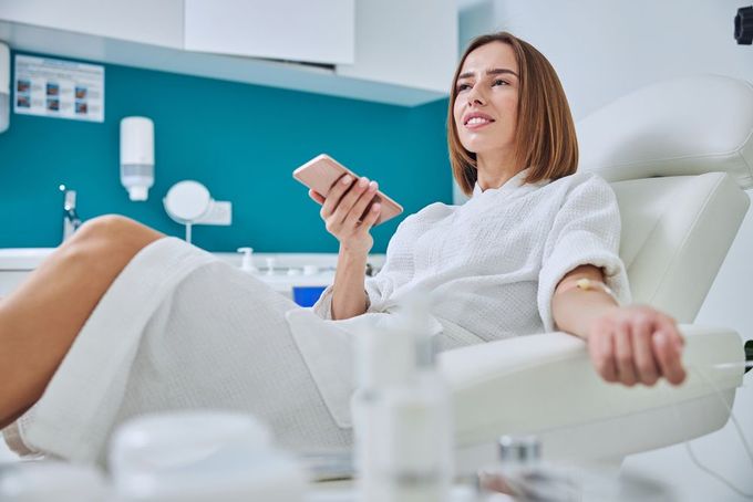 Woman relaxing in a hospital bed, holding a remote in a bright room