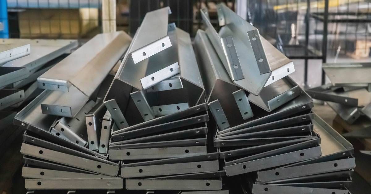 A pile of metal products that have been bent into shape sitting on top of each other on a wood pallet in a warehouse.