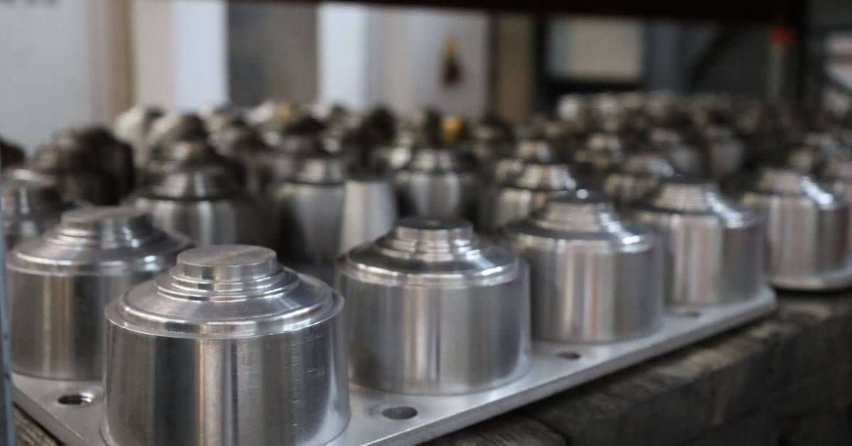 A close-up of rows of custom machined metal parts stacked closely together on a shelf in an industrial warehouse.