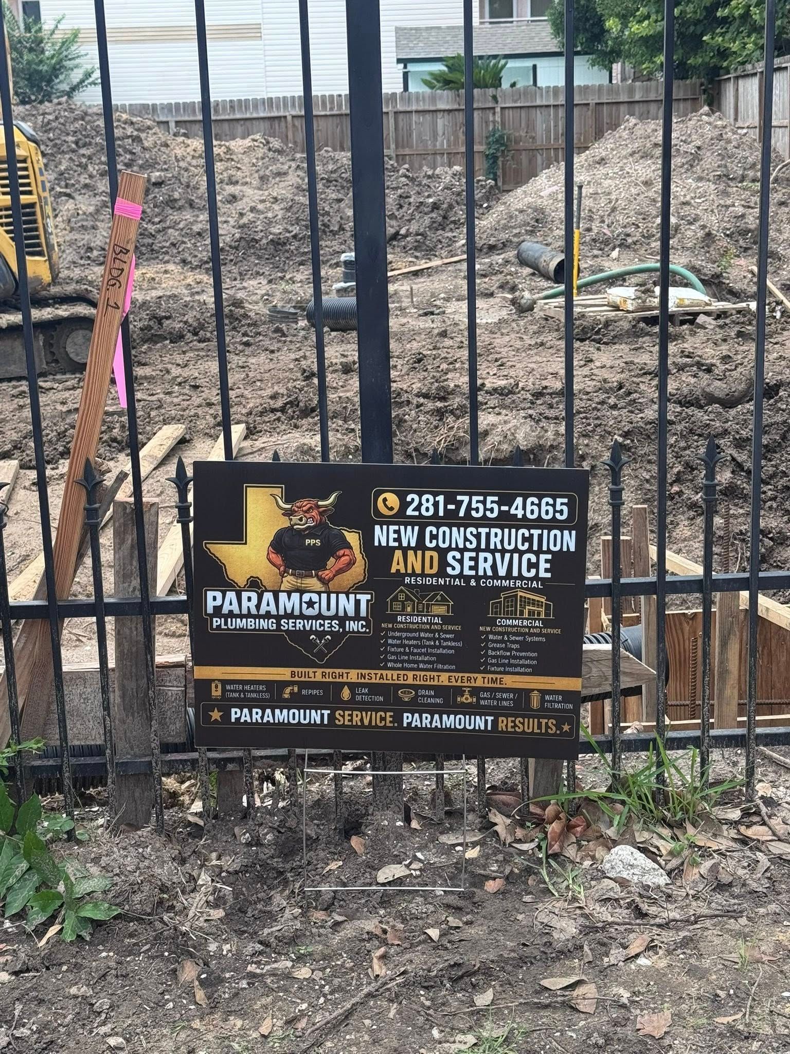 Black Paramount debris removal sign on a chain-link fence at a rubble-filled construction site.