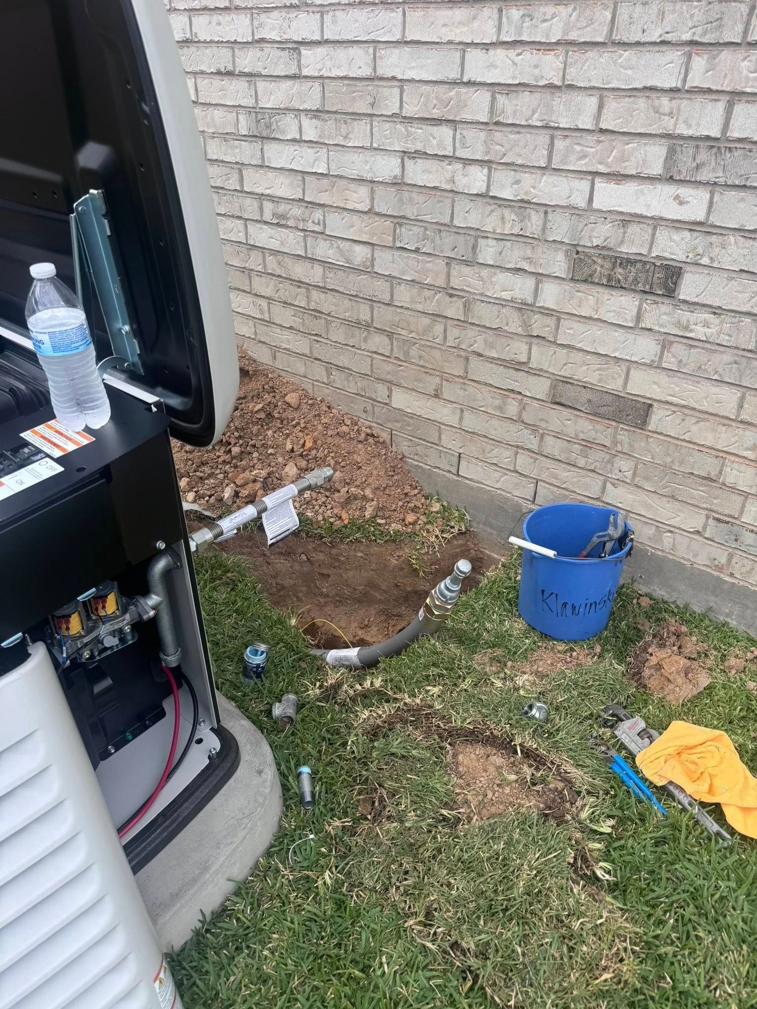 Outdoor side yard with brick wall, blue bucket, yellow gloves, and a truck parked nearby.