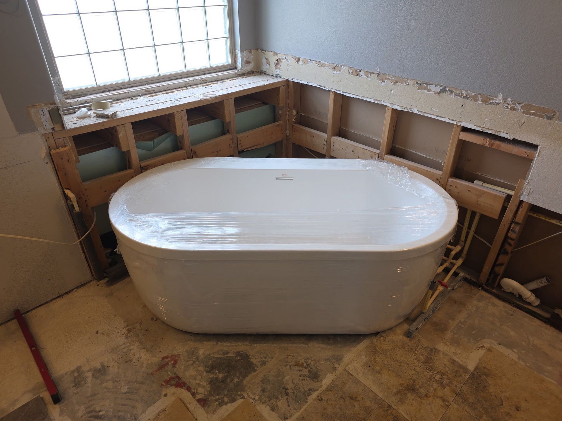 Bathroom under renovation with a freestanding white tub and exposed wall framing
