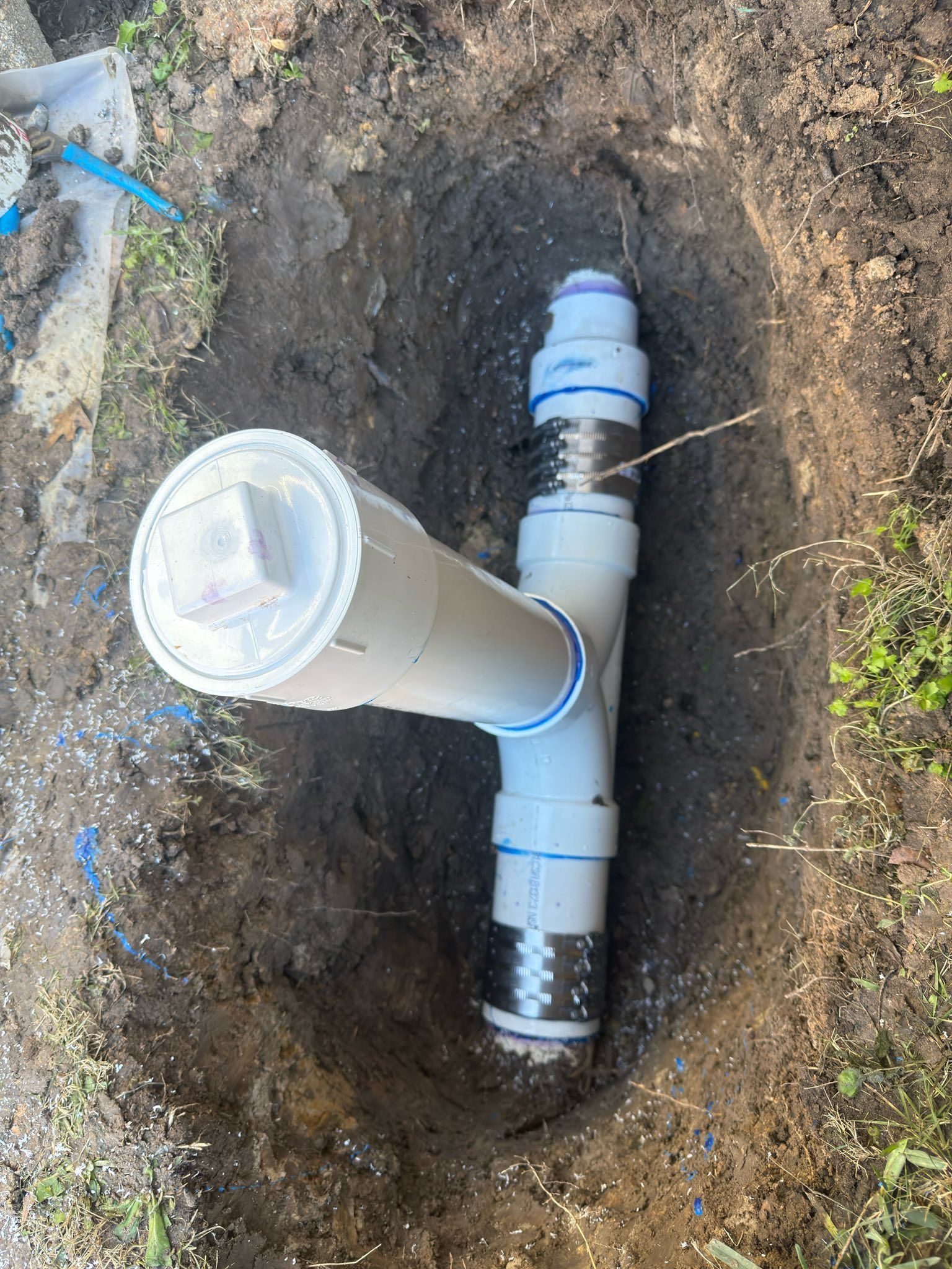 Underground PVC pipes and fittings in a dirt trench during plumbing repair