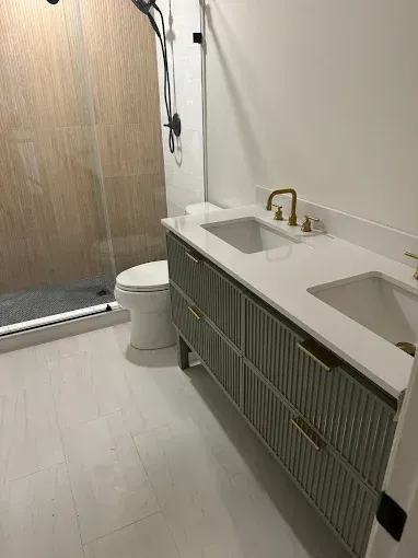 Modern bathroom with double sink vanity, toilet, and wood shower door.