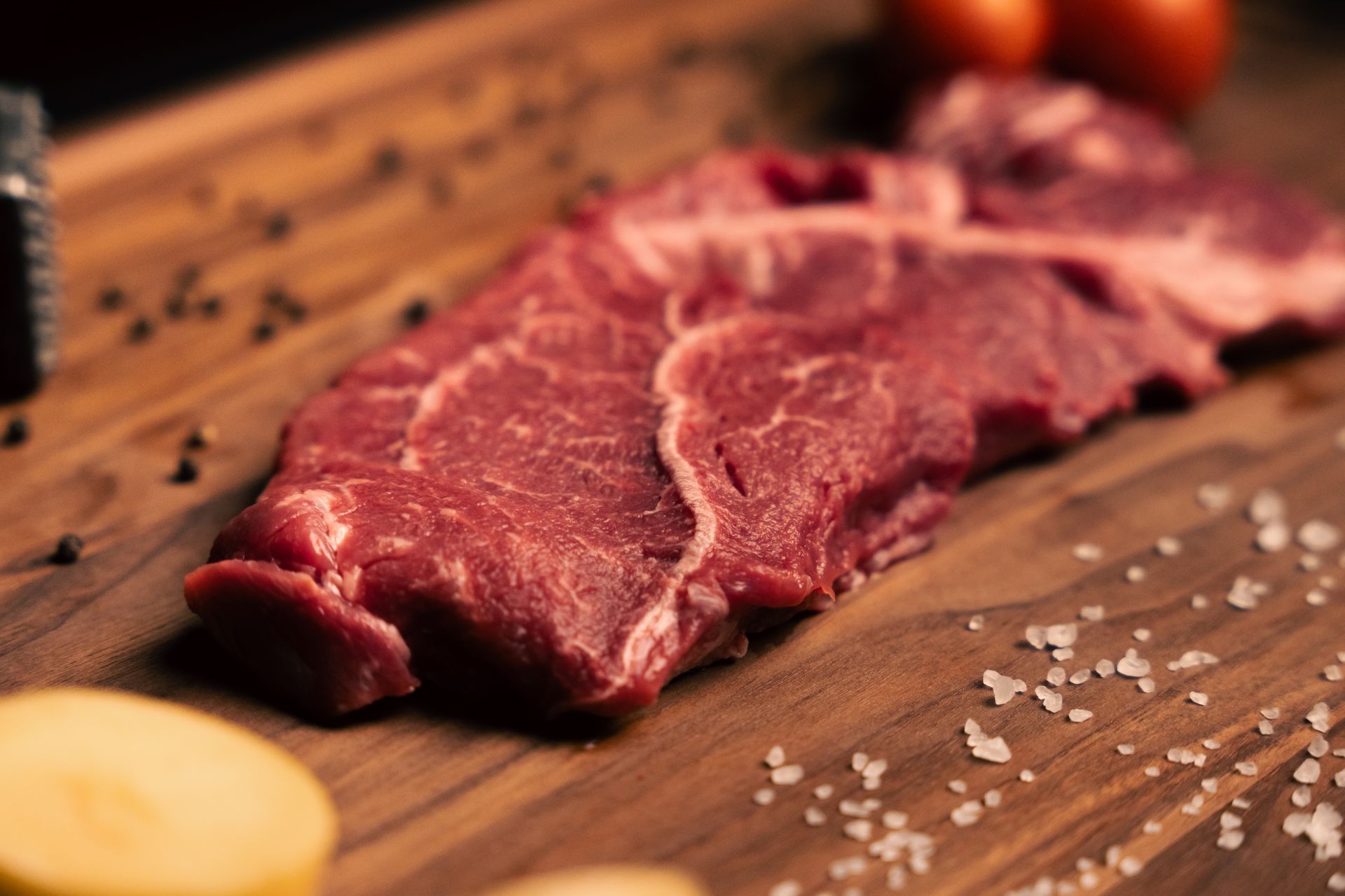 A piece of raw steak is sitting on a wooden cutting board.