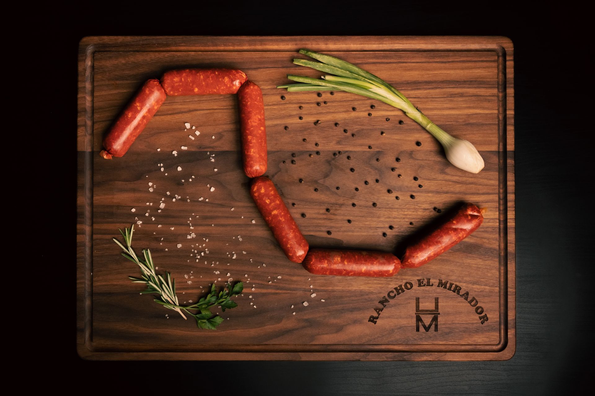 A wooden cutting board with sausages and onions on it