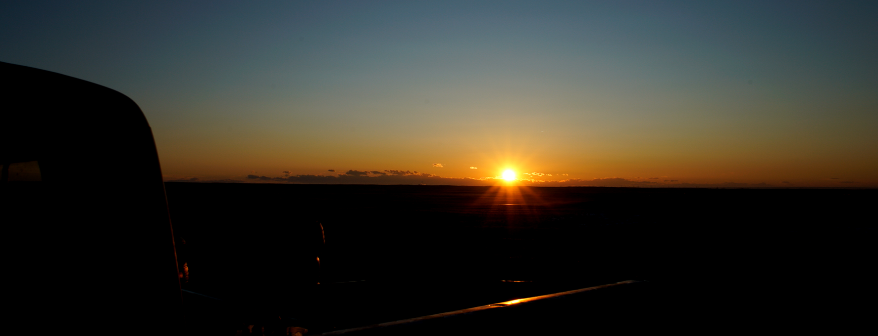 The sun is setting over a desert landscape.