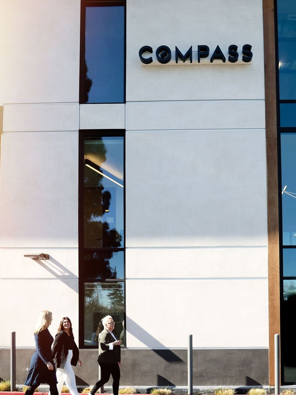 Modern building facade with COMPASS sign and pedestrians walking outside