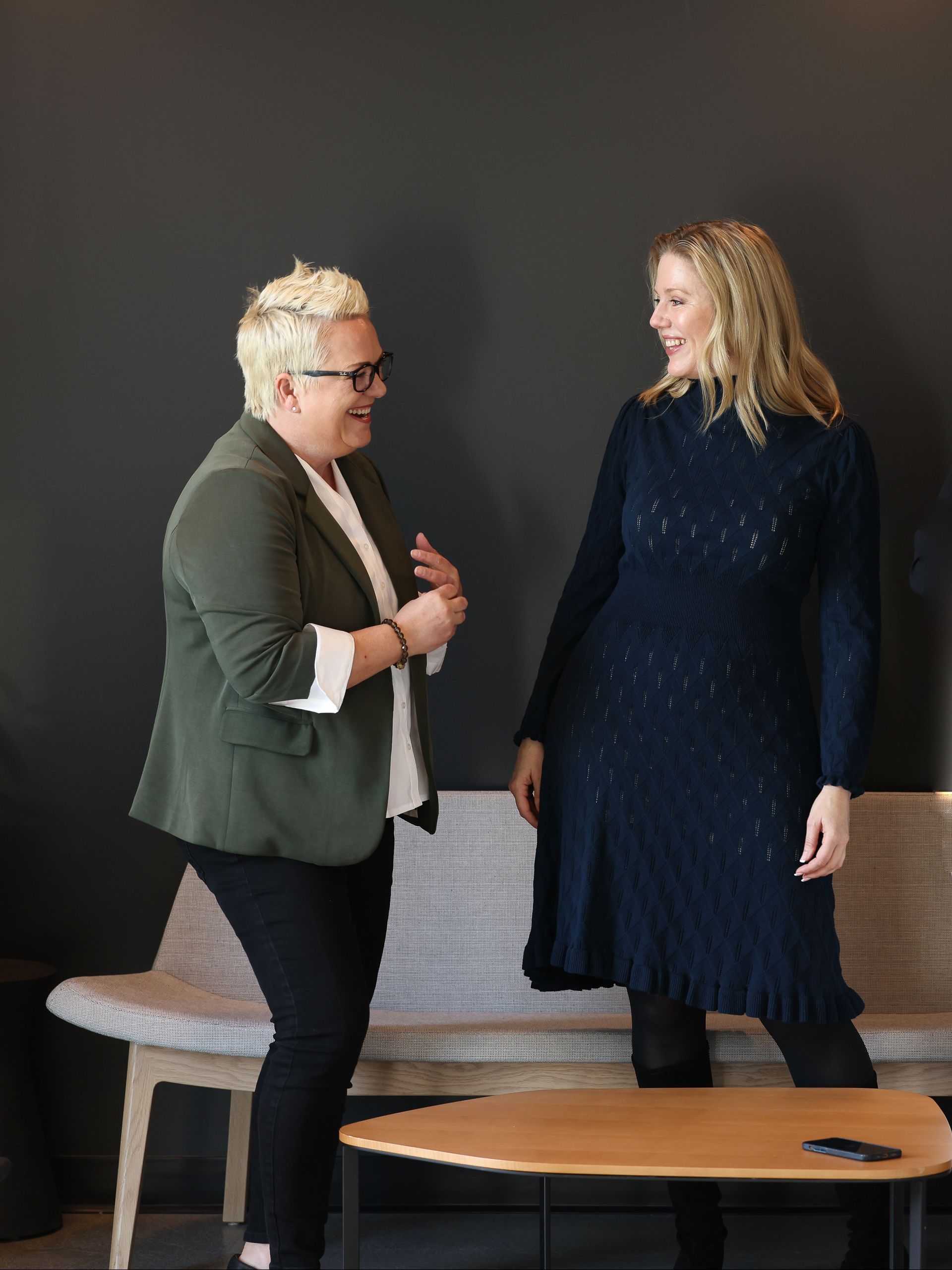 Two people talking in a modern room beside a bench and round table