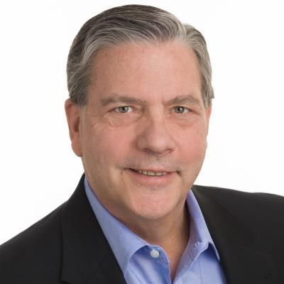 A man in a suit and blue shirt is smiling for the camera