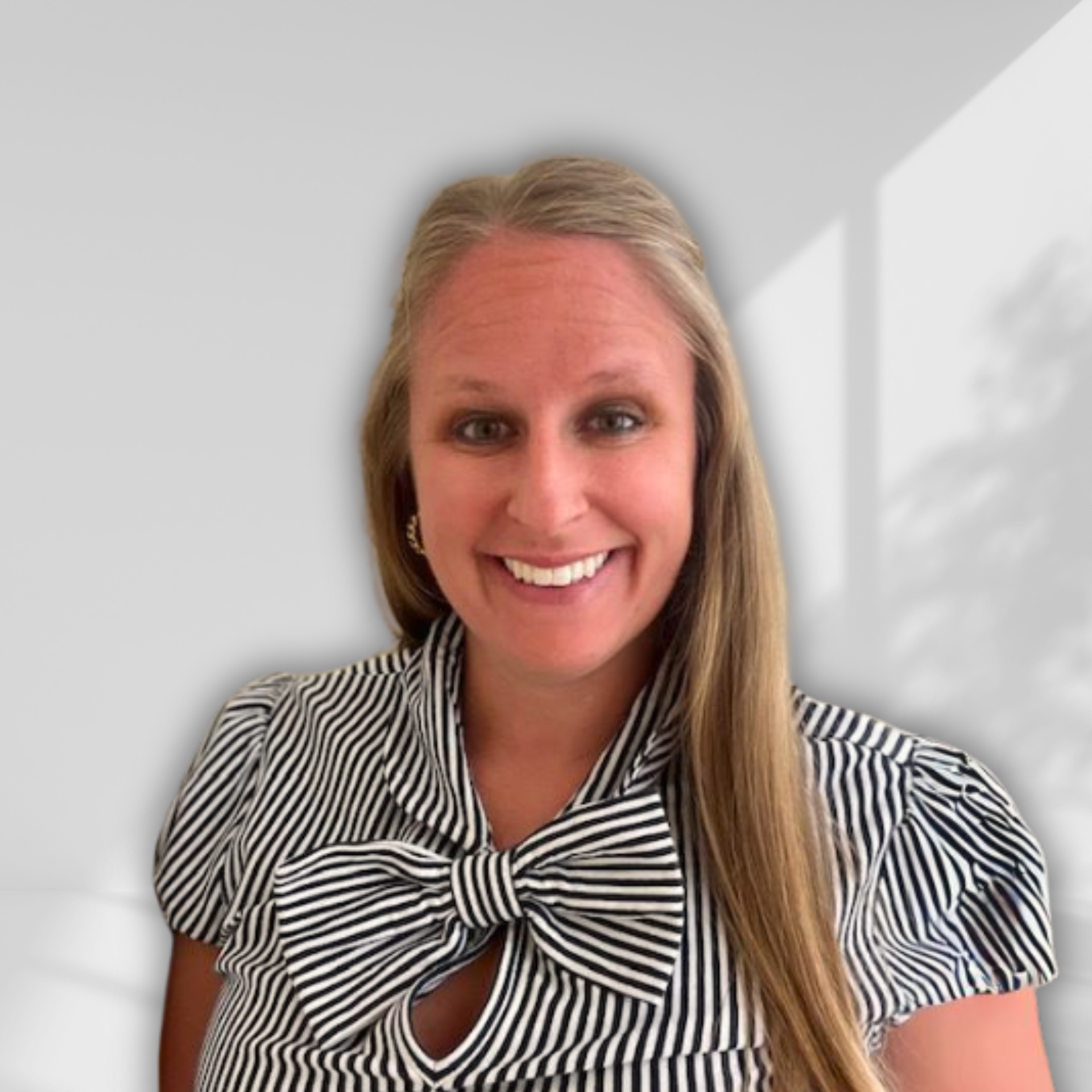 A woman wearing a black and white striped shirt with a bow is smiling.
